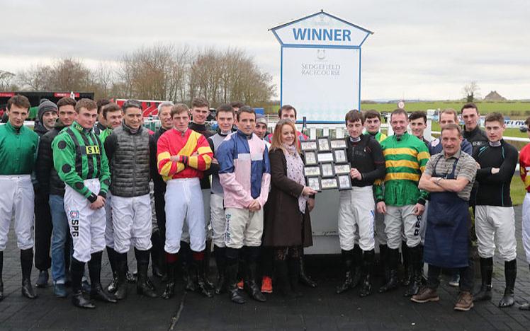 Group of jockeys posing for a photo in the parade ring at Sedgefield Racecourse.