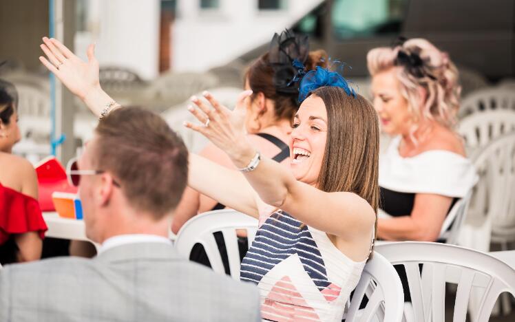 A race goer gesturing to a friend in a friendly way at Sedgefield Racecourse